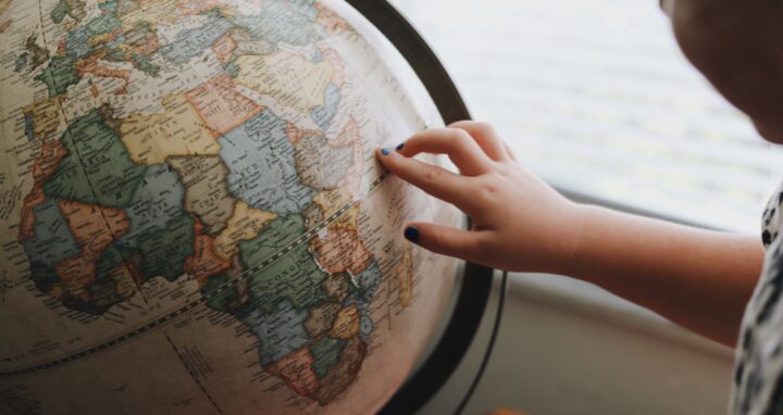 Someone pointing at a location on a globe.